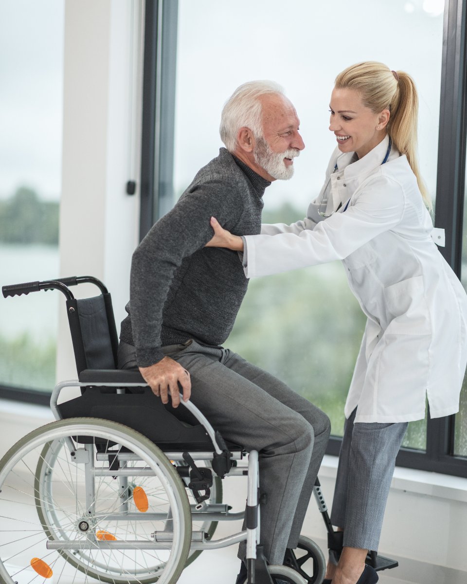 Support worker helping a participant stand from his wheelchair